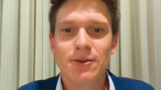 Lucas está de terno azul, camisa azul clara e sem gravata. Ele dá seu depoimento sobre hipnoterapia para crenças limitantes.
