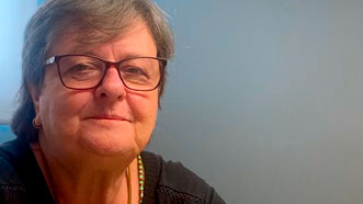 Rosângela veste uma camisa preta, tem cabelos curtos e está de óculos. Ela dá seu depoimento sobre a hipnoterapia para burnout e raiva